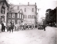 Parade Coming c. 1930....Greenwood Avenue near the south end of P.T. Barnum Square. The two wood frame buildings in the left of the photo were razed in the early 1960s and have been replaced by P.T. Barnum Plaza. The house, exhibiting the American flag, was home to a tailor shop operated by J.M. Thurner.
